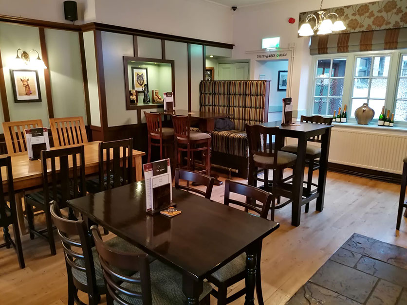 Cosy dining area at The Talbot Inn pub and restaurant in Stilton, Cambridgeshire with wooden tables, chairs and welcoming decor.